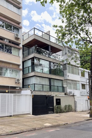 A modern multi-story building with balconies, large windows, and a garage door marked with the number 243. - 10 Minutos Da Praia De Ipanema | Vm201 (Rio de Janeiro)