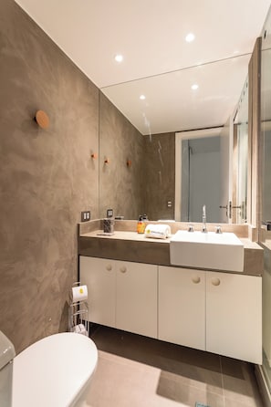 A modern bathroom with a white toilet, a sink with a mirror, and a shower area. - 10 Minutos Da Praia De Ipanema | Vm201 (Rio de Janeiro)