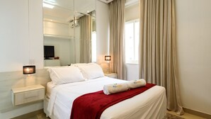 Ein Hotelzimmer mit einem großen Bett, einem Nachttisch, einem Fernseher und einem Spiegel.