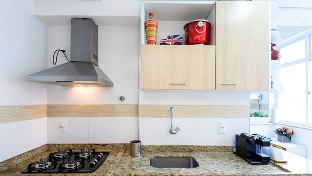 Eine moderne Küche mit Gasherd, Edelstahlspüle und Holzschränken.