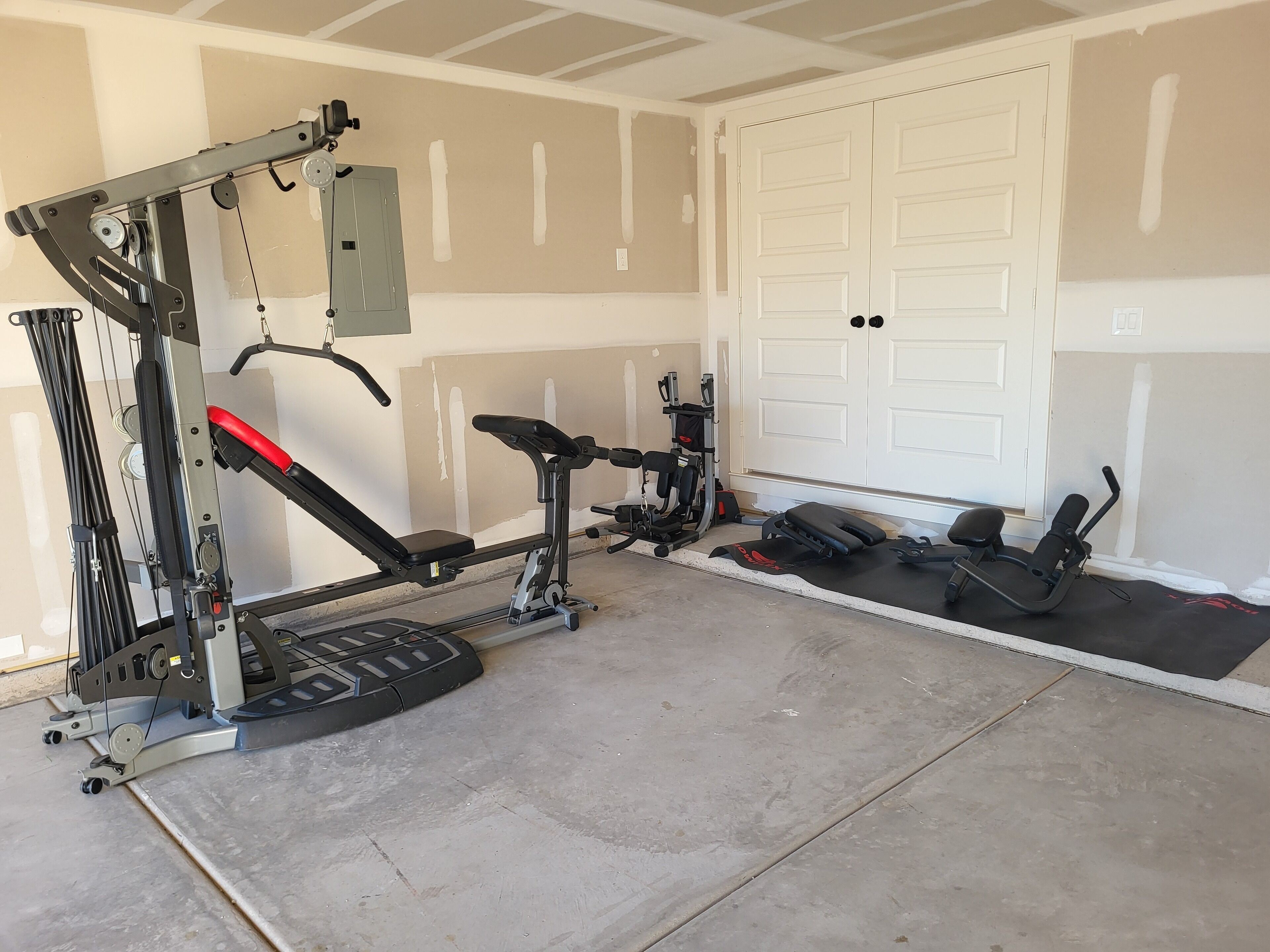 A home gym with exercise equipment, including a bench press, a squat rack, and a bench.