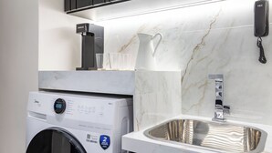 A modern laundry area with a front-loading washing machine, a sink, and a marble countertop. - Perfeito Para Casais Em Ipanema | Vp802 (Rio de Janeiro)