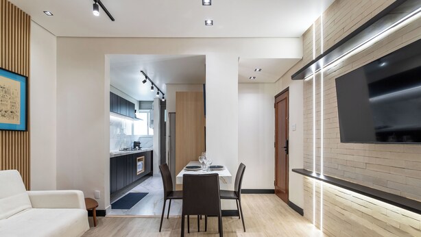 A modern living room with a dining area, a kitchen in the background, and a TV mounted on the wall. - Perfeito Para Casais Em Ipanema | Vp802 (Rio de Janeiro)