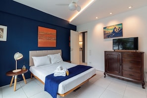 Une chambre à coucher comprenant un lit, une table de chevet, une lampe, une commode et des œuvres d’art accrochées aux murs.