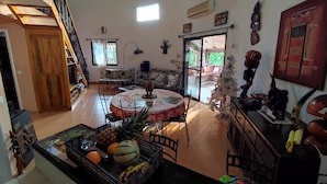 A spacious living area with a high ceiling, a staircase, a dining table with chairs, a Christmas tree, and a kitchen area with a fruit crate. - Villa pool, residence pools, beach, seaside, beach restaurant (Saly,Région de Thiès)