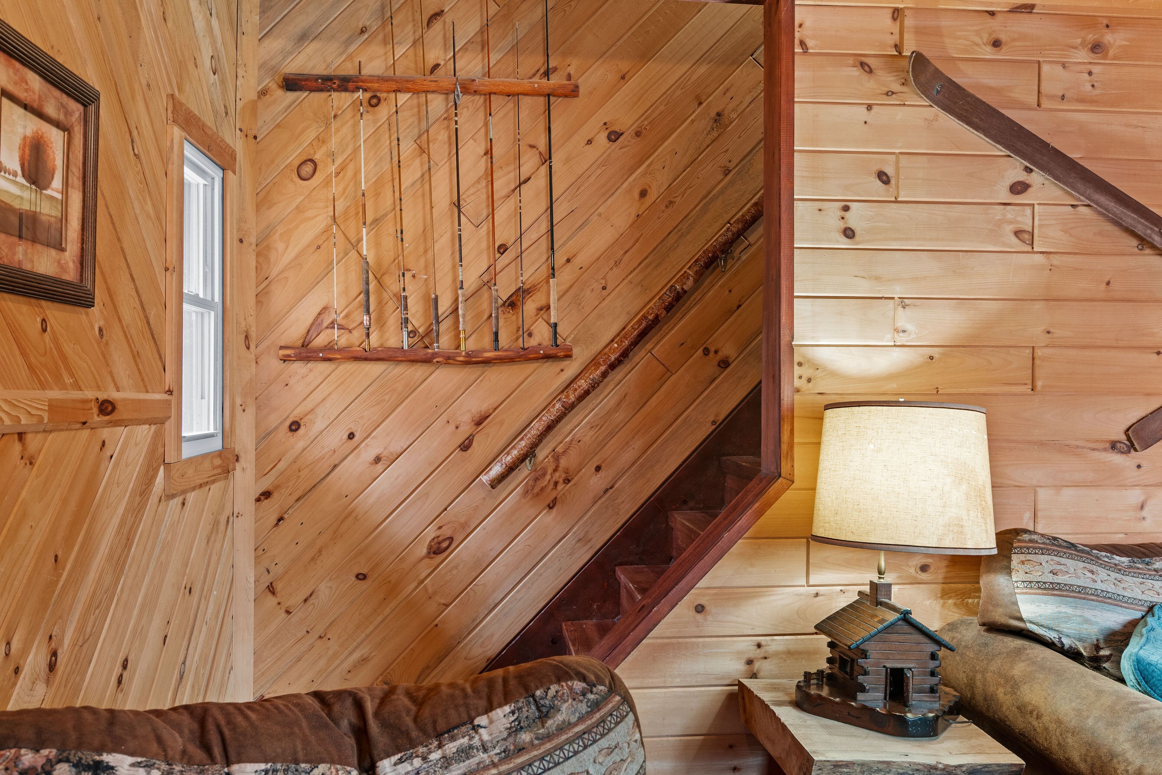 Un interior de madera con techo inclinado, escalera de madera, lámpara y sofá.