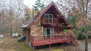 Eine Holzhütte mit steinernen Fundamenten, einer Holzterrasse und einem Balkon.