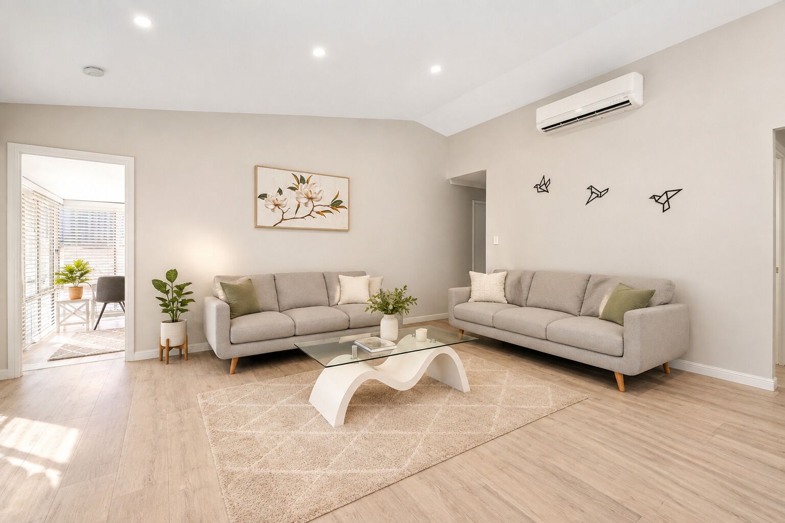 A modern living room with two sofas, a glass coffee table, and a large window.