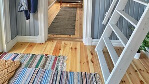 Ein Zimmer mit Holzboden, einer Couch, einem Couchtisch, einer Treppe und einem an der Wand befestigten Kleiderhaken.