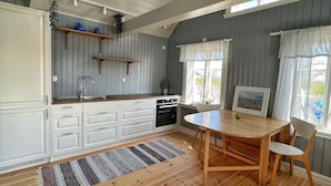 Eine moderne Küche mit weißen Schränken, einem Holzespeisetisch und Blick ins Freie.