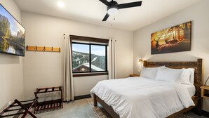 Ein Schlafzimmer mit Bett, Deckenventilator, Fenster mit Bergblick und einem Bild an der Wand.