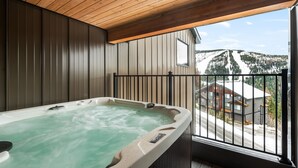 Ein Whirlpool in einem Raum mit Holzwänden und Blick auf einen verschneiten Berg.