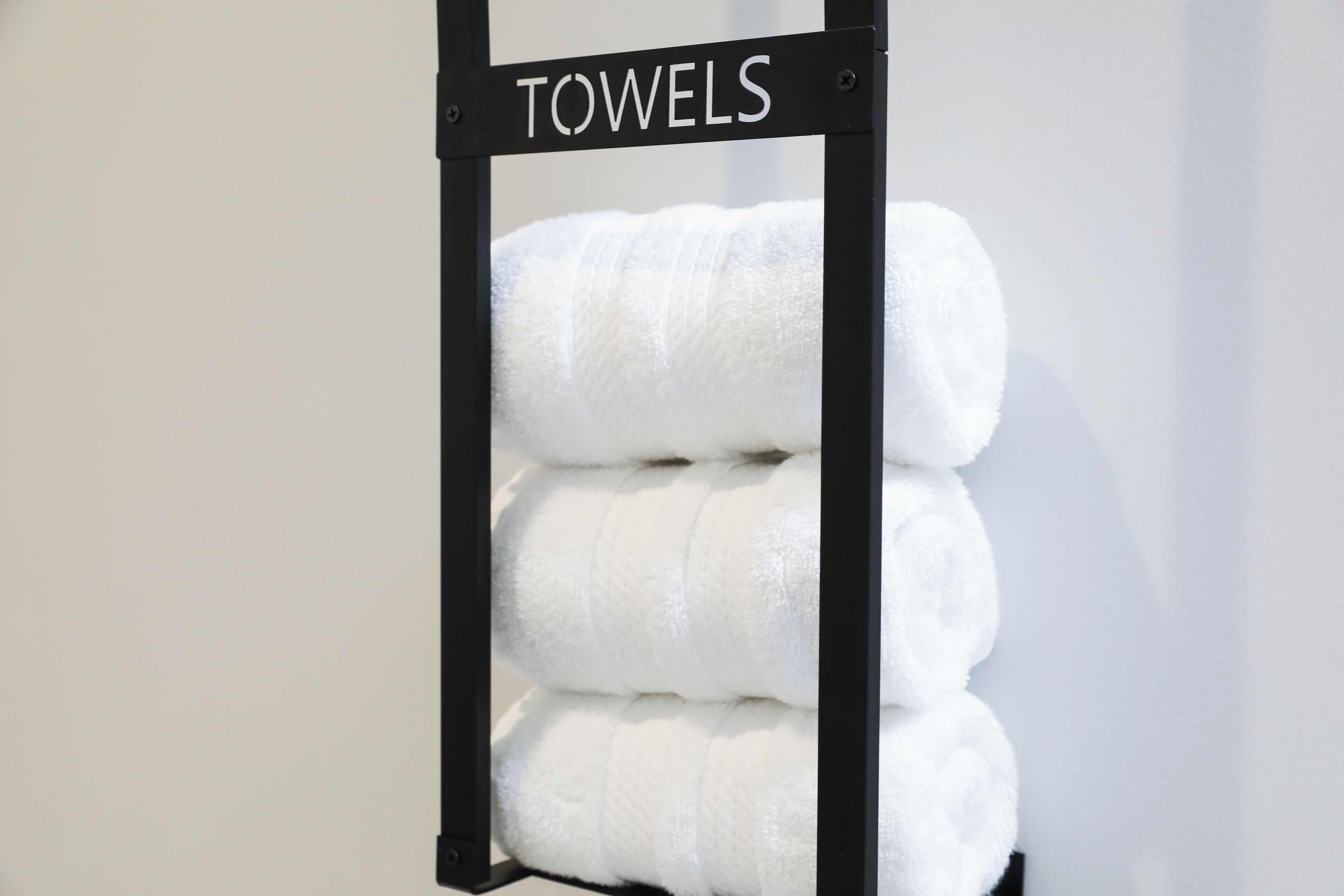 Une pile de serviettes blanches est posée sur un porte-serviettes portant l’inscription « SERVIETTES ».