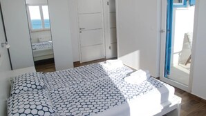 A bedroom with a bed, a wardrobe, and a door leading to a balcony.