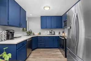 Une cuisine moderne avec des armoires bleues, des appareils en acier inoxydable et un plancher en bois.