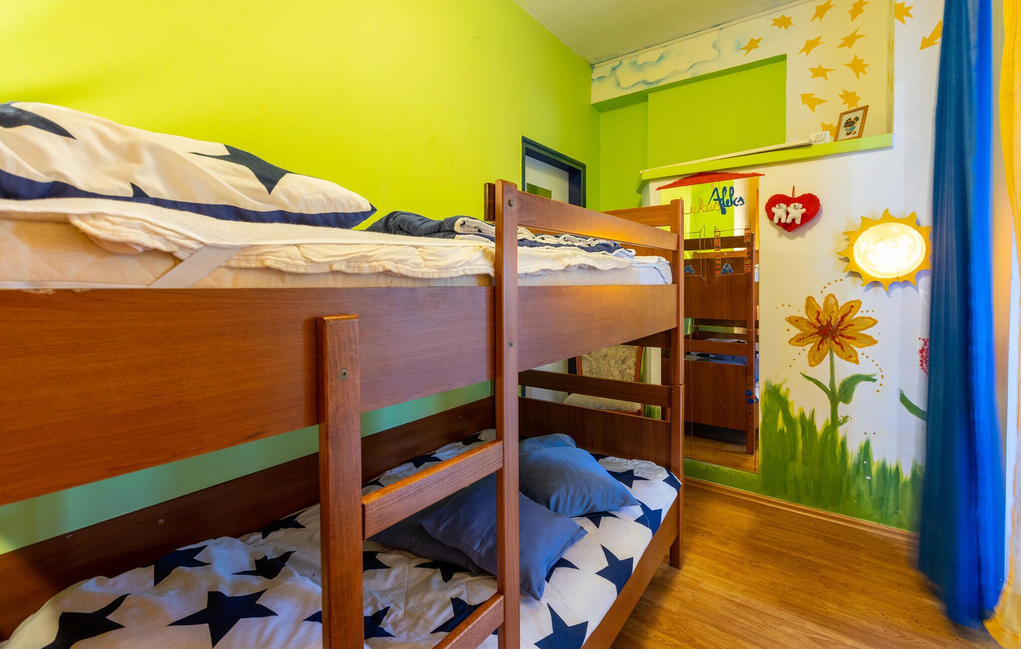 A bunk bed room with green walls and a mural.