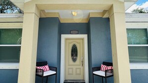 A house with a beige entrance, two chairs with cushions, and a blue wall. - The Blue Oasis, a beach-themed Florida getaway (Tampa)