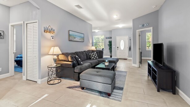 A modern living room with a sectional sofa, a coffee table, and a television. - The Blue Oasis, a beach-themed Florida getaway (Tampa)