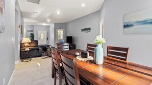 A dining area with a wooden table, chairs, and a vase with flowers. - The Blue Oasis, a beach-themed Florida getaway (Tampa)