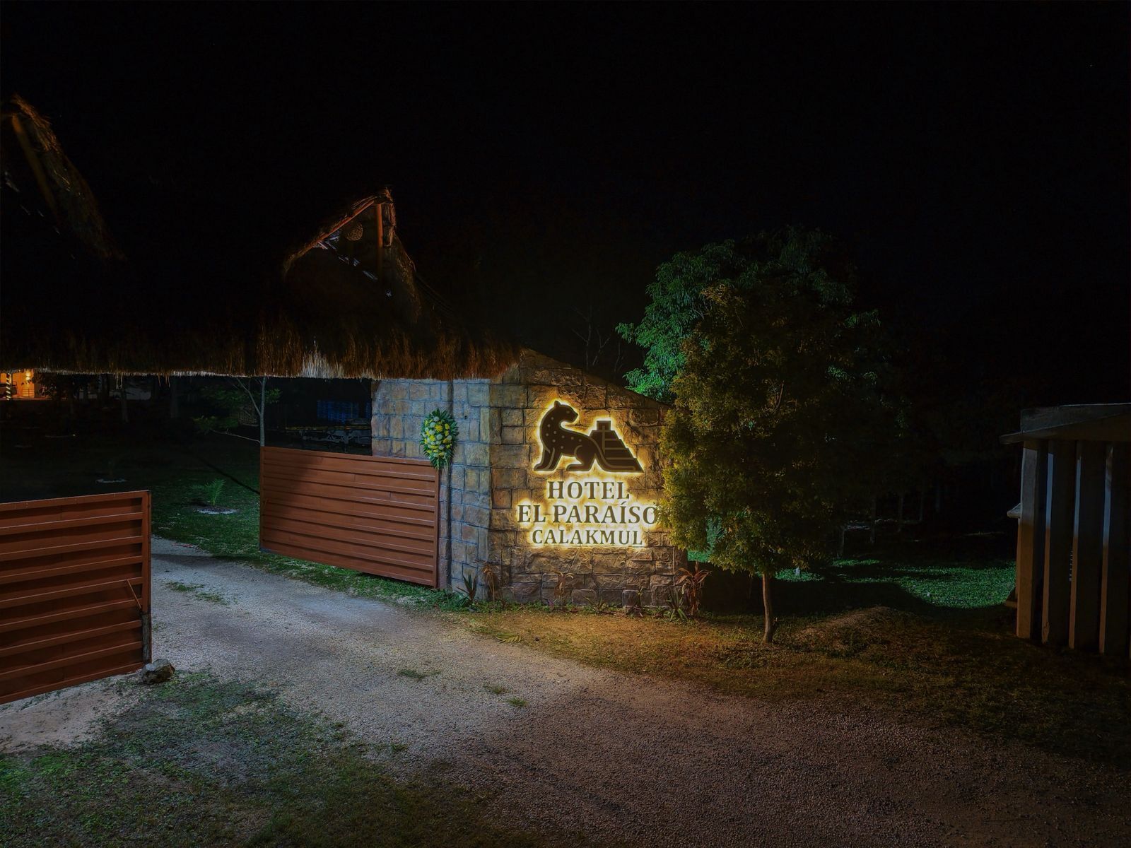 Entrada de un hotel de noche, con un cartel que dice "HOTEL EL PARAÍSC CALAKMUL".