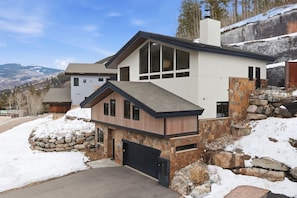 A modern two-story house with a stone facade, large windows, and a garage.