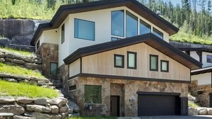 A modern two-story house with a stone facade, large windows, and a garage.
