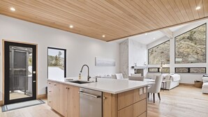 A modern kitchen with wooden cabinets, a built-in dishwasher, and a large island with a sink.