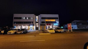 A multi-story building with a 'BASE' sign, a 'Glassair' sign, and a 'Bowl of Soup' sign. There are several cars parked in front. - Base apartments Iceland - cozy studio apartment - capital area (Hafnarfjörður)