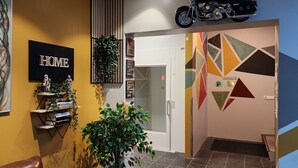 A modern lobby with a leather sofa, a motorcycle mounted on the wall, and a 'HOME' sign. - Base apartments Iceland - cozy studio apartment - capital area (Hafnarfjörður)