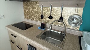 A kitchen with wooden cabinets, a black microwave, a sink with a faucet, and a stove. - Ocean Breeze Apt #2 - 1BR 2Beds with pool (Oranjestad)