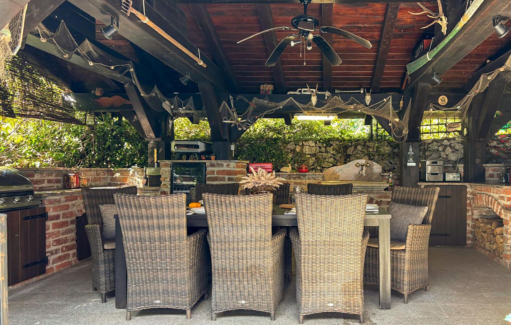 Eine Terrasse im Freien mit Korbmöbeln, einer Steinmauer und einem Grill.