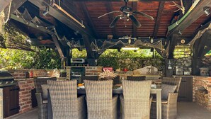 An outdoor patio with wicker furniture, a stone wall, and a grill. - 3 bedroom gorgeous home in Krasica (Krasica)