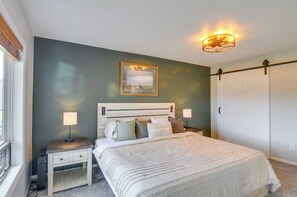 Een slaapkamer met een bed, twee nachtkastjes, een wandlamp, een plafondlamp en een deur.