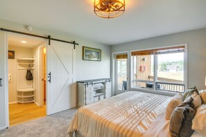 A bedroom with a bed, a desk, a chair, a wardrobe, and a sliding door leading to a balcony.