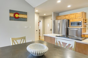 A modern kitchen with stainless steel appliances, wooden cabinets, and a dining area with a unique white bowl centerpiece. - Cozy Condo with Mountain Views Nearby Hot Springs (Pagosa Springs)