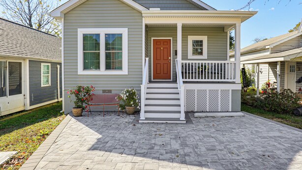 A two-story house with a front porch, a brown door, and a small garden area with potted plants. - Walk to Historic Chestertown: Dog-Friendly Retreat (Chestertown)
