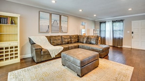 A spacious living room with a sectional sofa, a coffee table, and a bookshelf. - Convenient Oasis in St Pete, 4 Mi to Pier & Dtwn! (St. Petersburg)