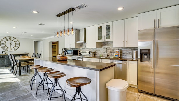 A modern kitchen with a central island, bar stools, stainless steel appliances, and a clock on the wall. - Convenient Oasis in St Pete, 4 Mi to Pier & Dtwn! (St. Petersburg)