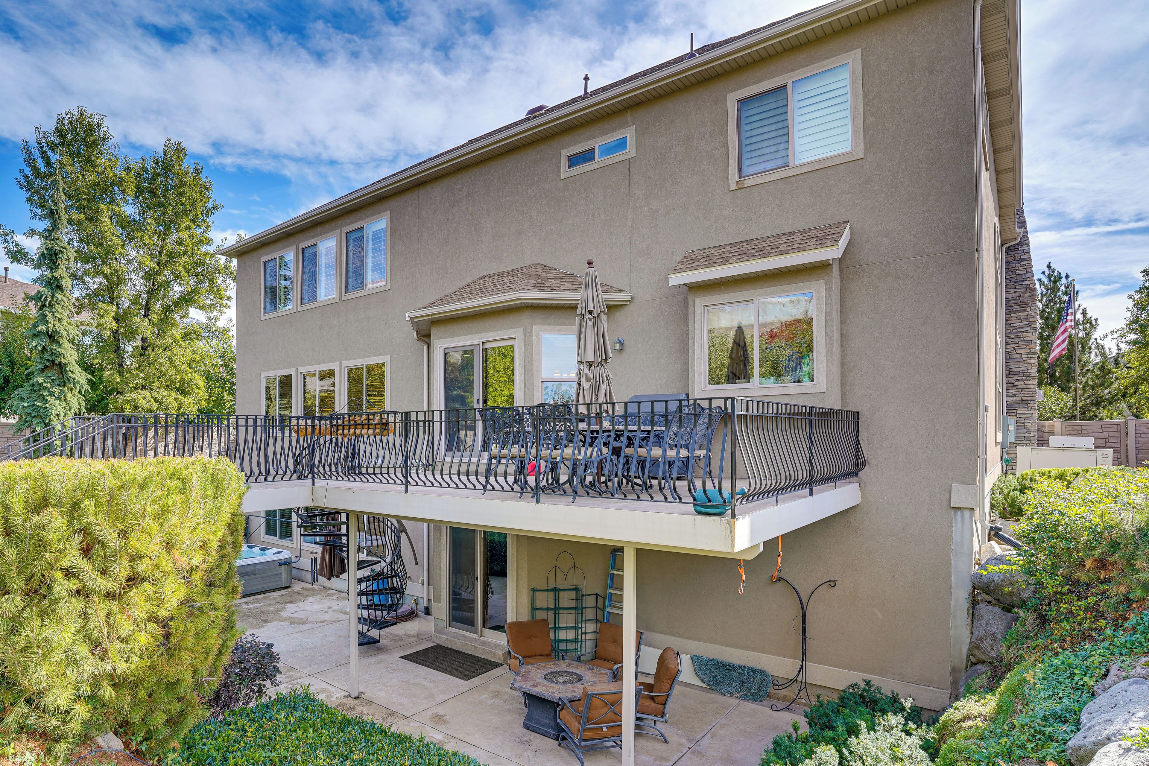 A two-story house with a balcony, outdoor seating, and a small garden.