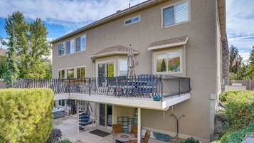 A two-story house with a balcony, outdoor seating, and a small garden.