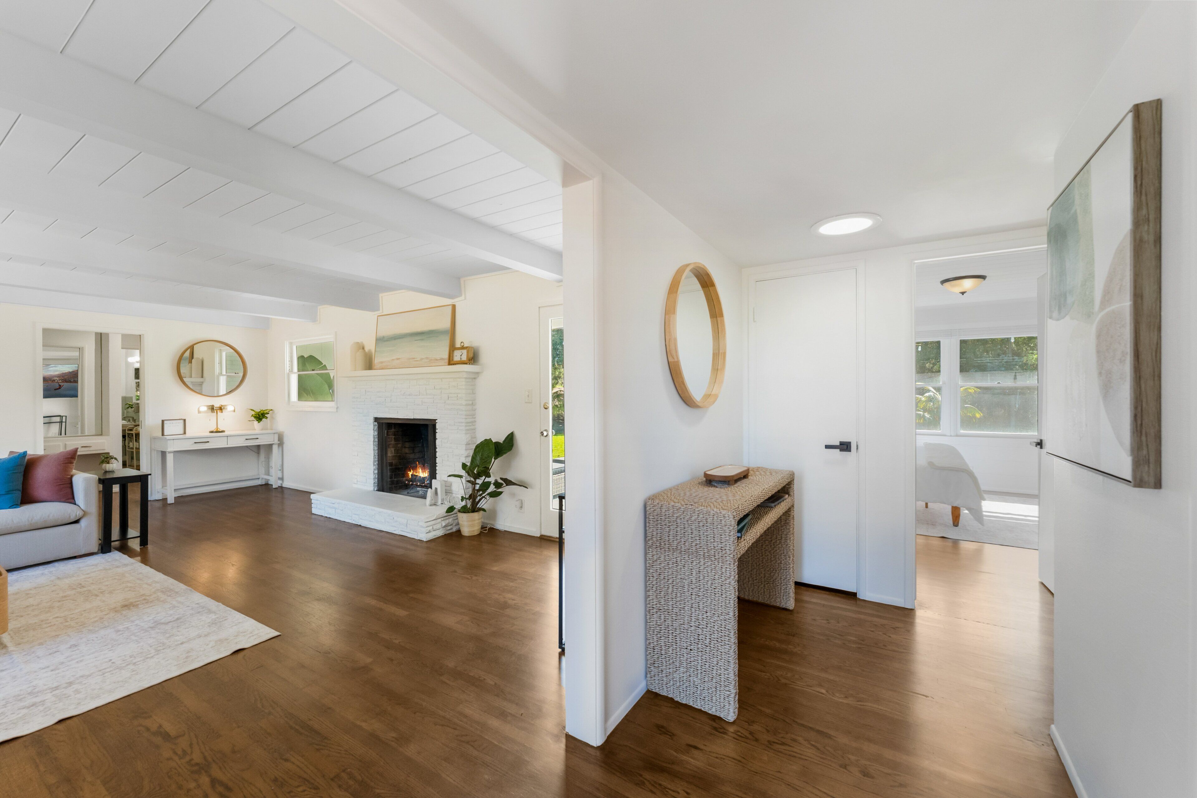A spacious living area with a fireplace, white walls, and wooden flooring.