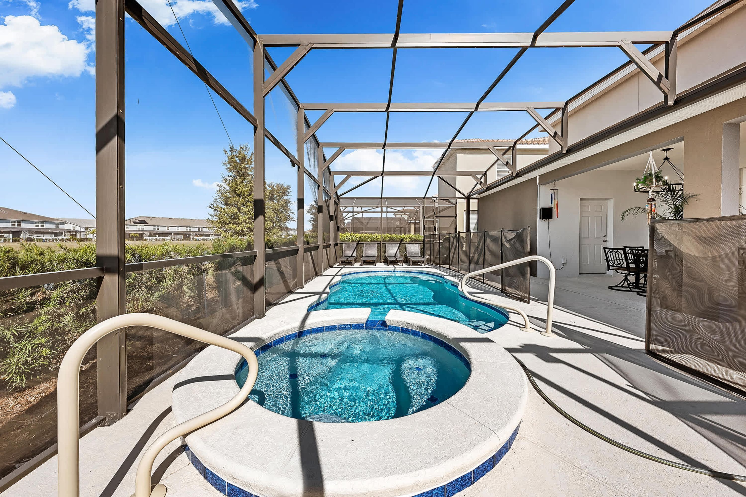Une piscine extérieure couverte, dotée d’une structure en forme de pergola, entourée d’une clôture et offrant une vue sur des immeubles résidentiels.
