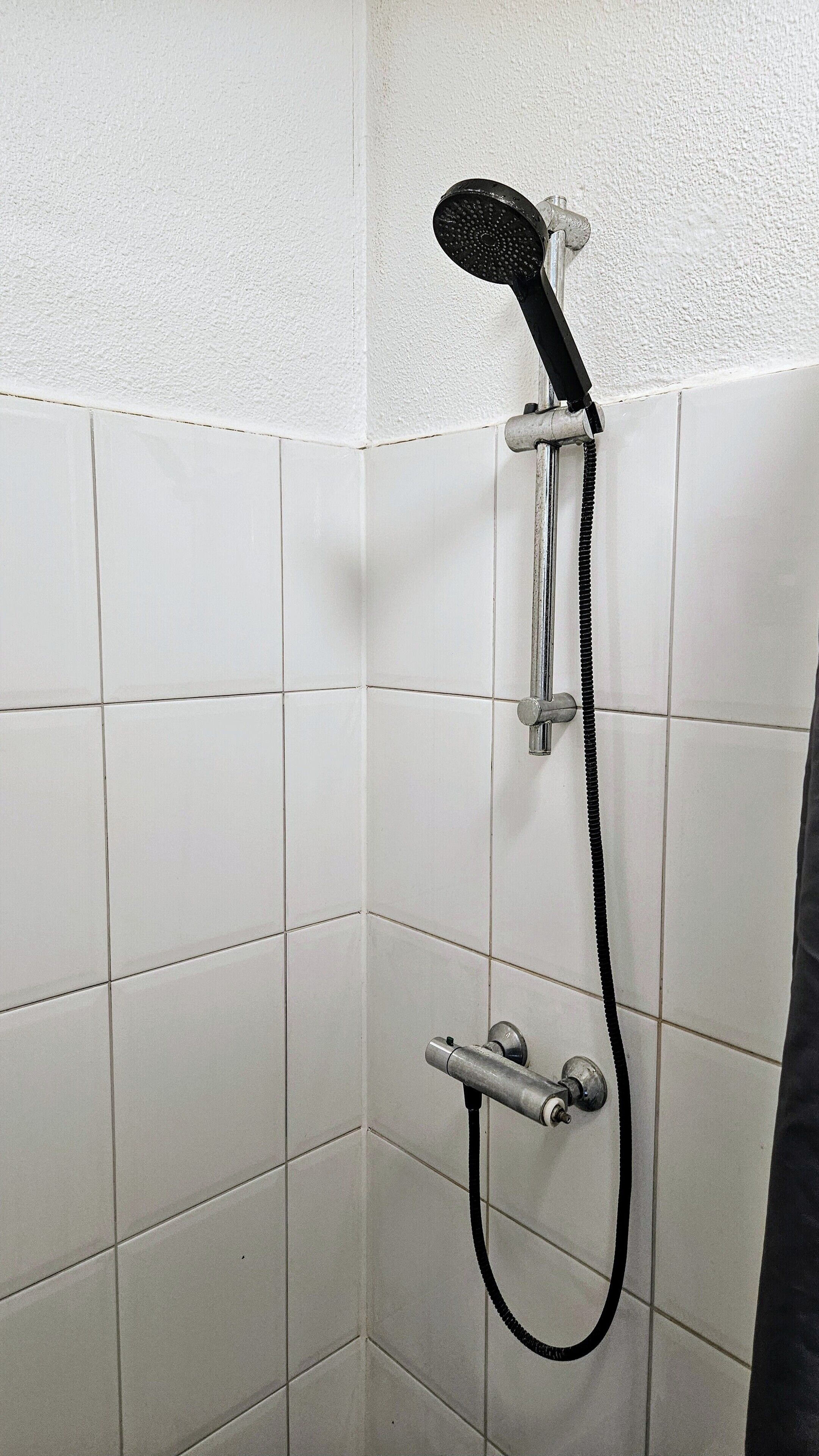 Una ducha con cabezal de ducha y manguera de mano.