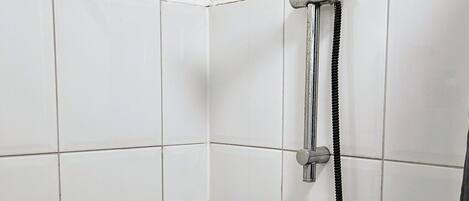 Una ducha con cabezal de ducha y manguera de mano.