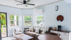 Un salon confortable avec un canapé, une table basse et des fauteuils, une table à manger et un ventilateur de plafond.