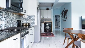 Una cocina moderna con salpicadero estampado, electrodomésticos de acero inoxidable y un comedor con sillas de madera.