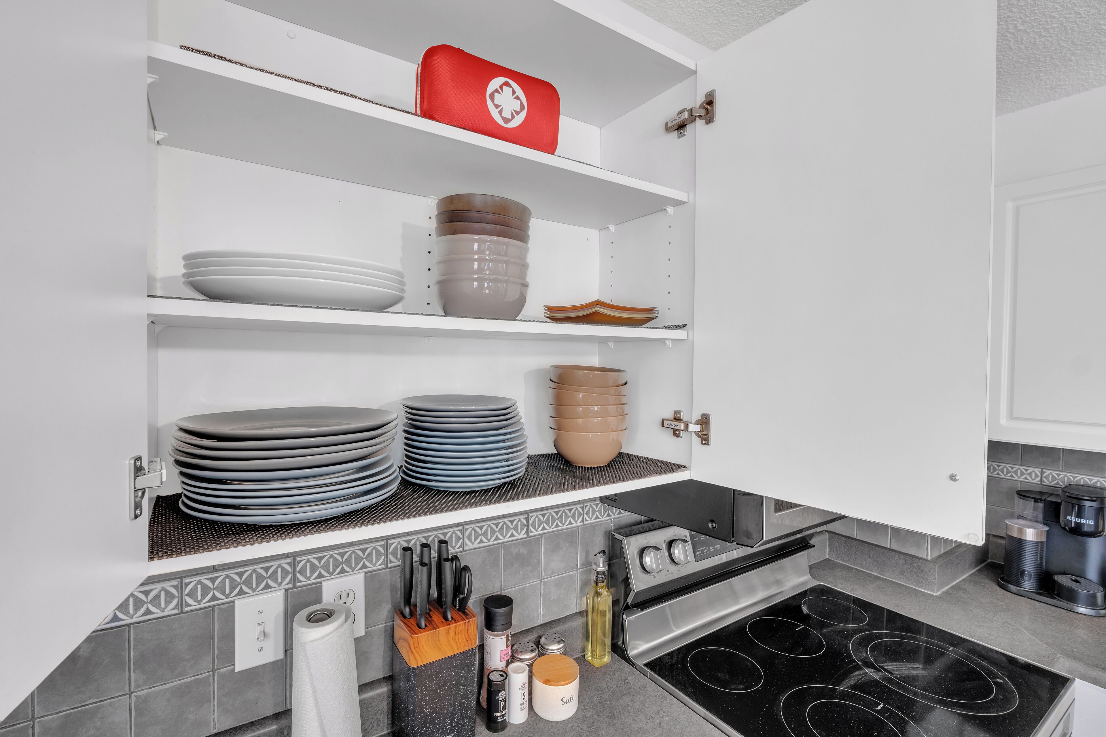Een keuken met witte kasten, een fornuis en diverse keukengerei.