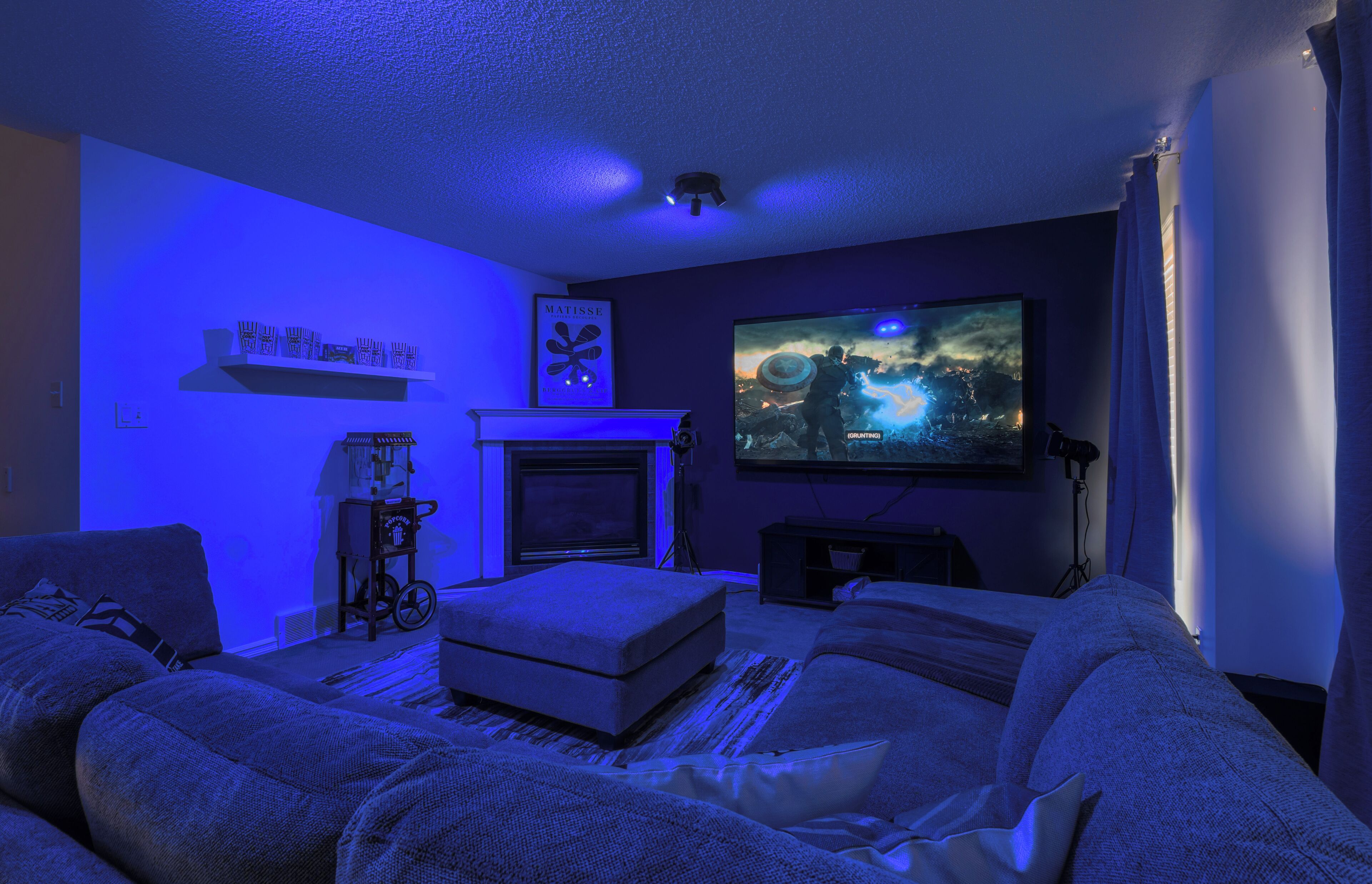 A cozy living room with a fireplace, a large flat-screen TV, and comfortable seating.