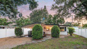A single-story house with a covered patio, a satellite dish, and a well-maintained lawn. - Charlotte Chalet | Private Yard & Play Set (Sarasota)