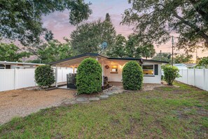 A single-story house with a covered patio, a satellite dish, and a well-maintained lawn. - Charlotte Chalet | Private Yard & Play Set (Sarasota)